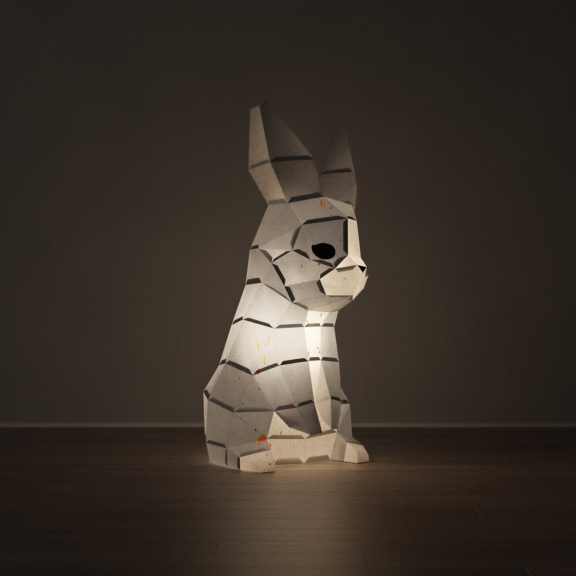 Sculpture en papier d'un lapin en origami 3D allumée, servant de veilleuse design dans une ambiance tamisée. Kit créatif au style épuré à monter soi-même avec un assemblage avec colle. Vu de côté la tête regarde vers la gauche 