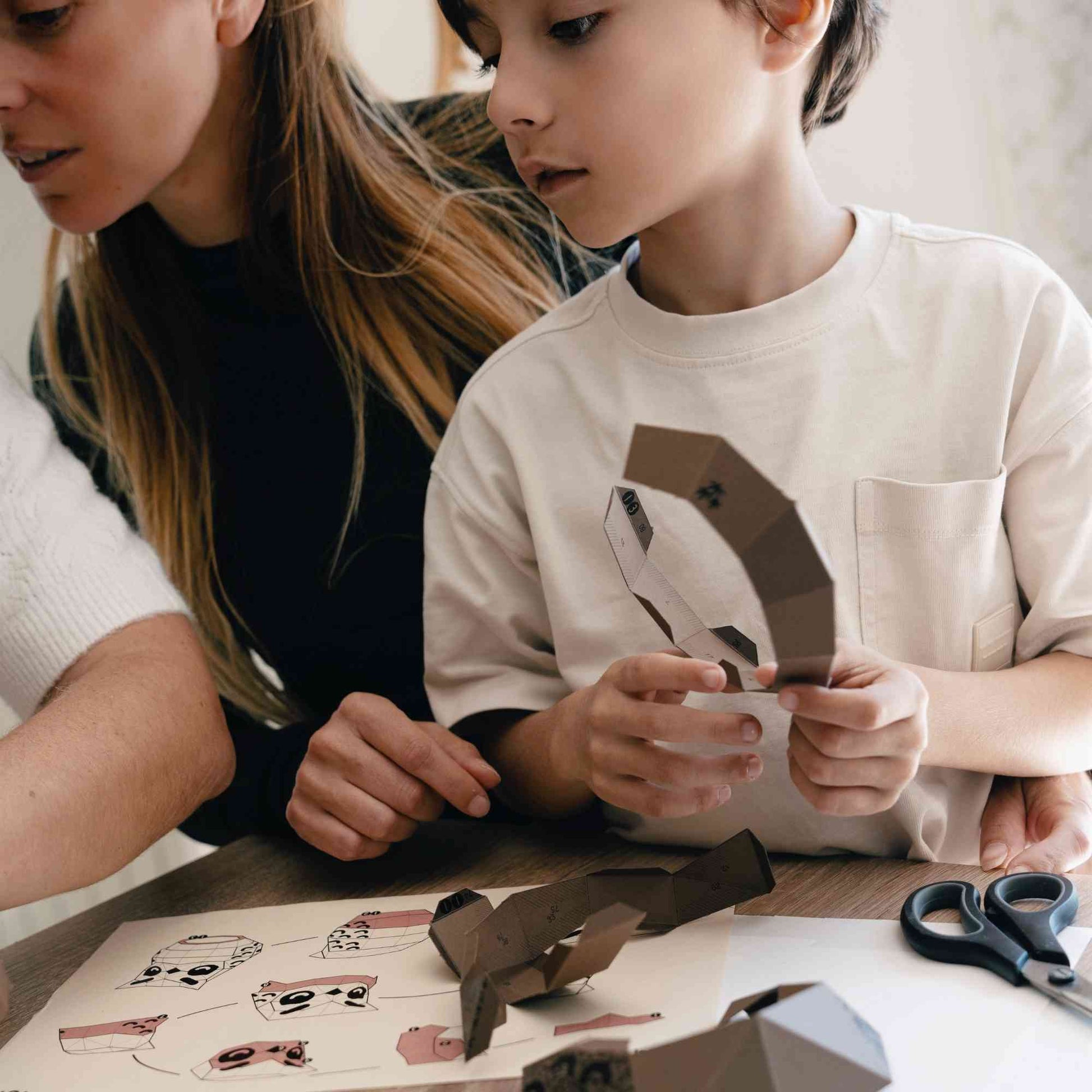 Un enfant et sa maman en plein loisir créatif papercraft en train de réaliser son hibou en papier.