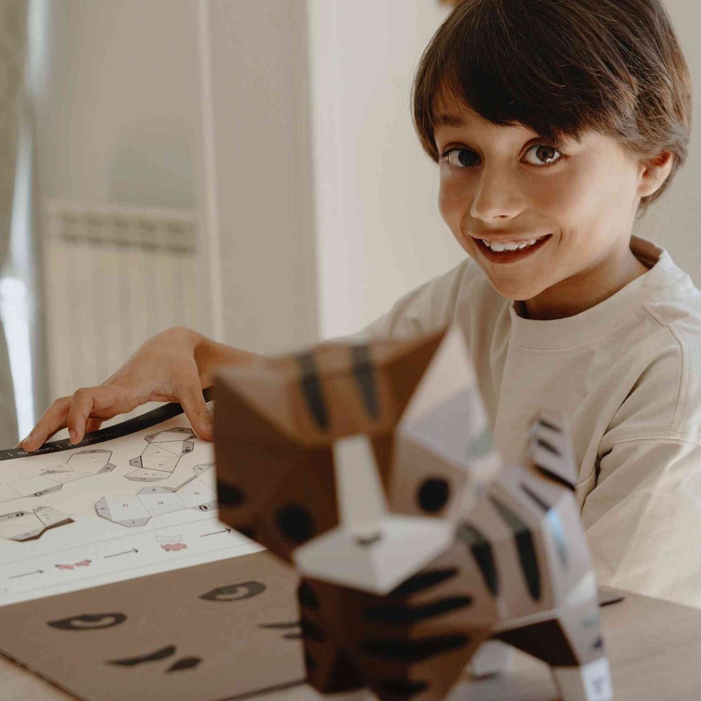 Un enfant en plein loisir créatif papercraft qui vient de réaliser son chat en papier.