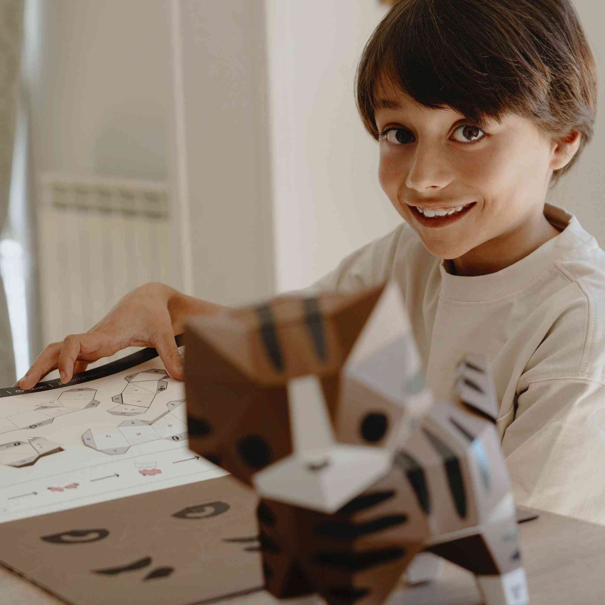 Un enfant en plein loisir créatif papercraft qui vient de réaliser son chat en papier.