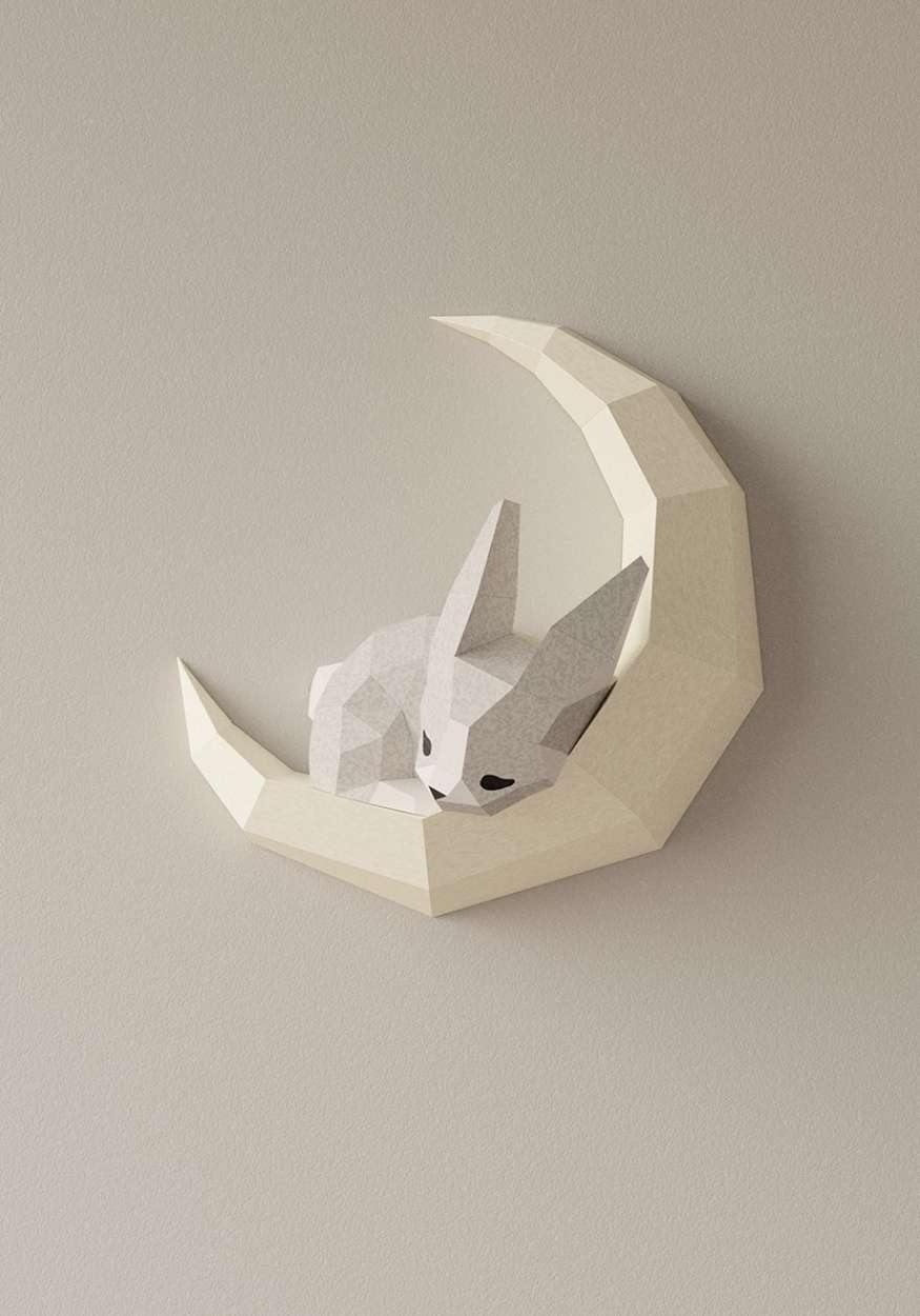 Photo en gros plan du wall art lapin. On voit l'applique murale de l'animal endormi sur la lune accrochée sur un mur. Le lapin est en papier papercraft 3D de style japonais origami