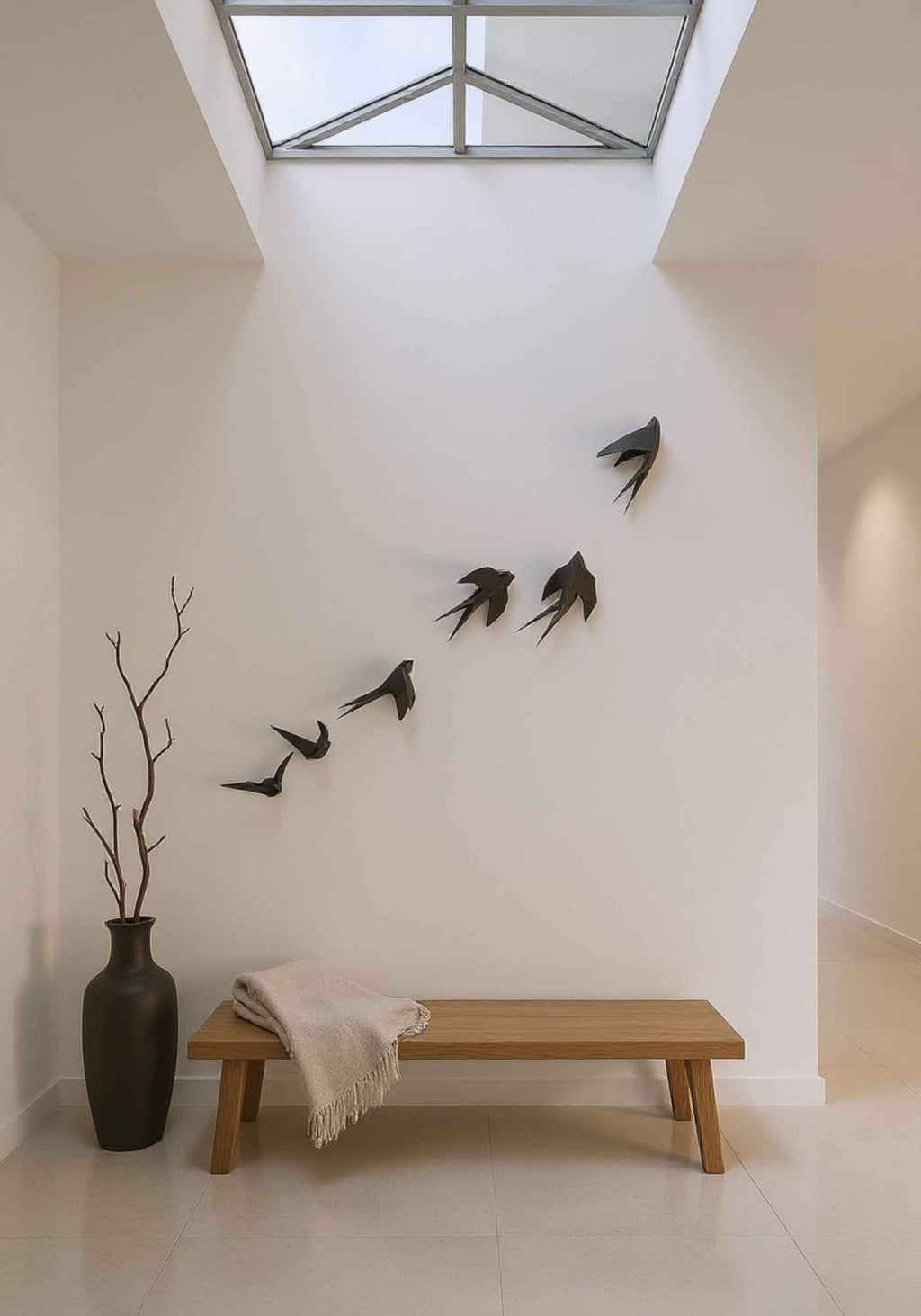 Mise en situation du wall art des 6 oiseaux en vol dans une maison. La déco intérieure est accrochée au mur blanc  au-dessus d'un banc.
