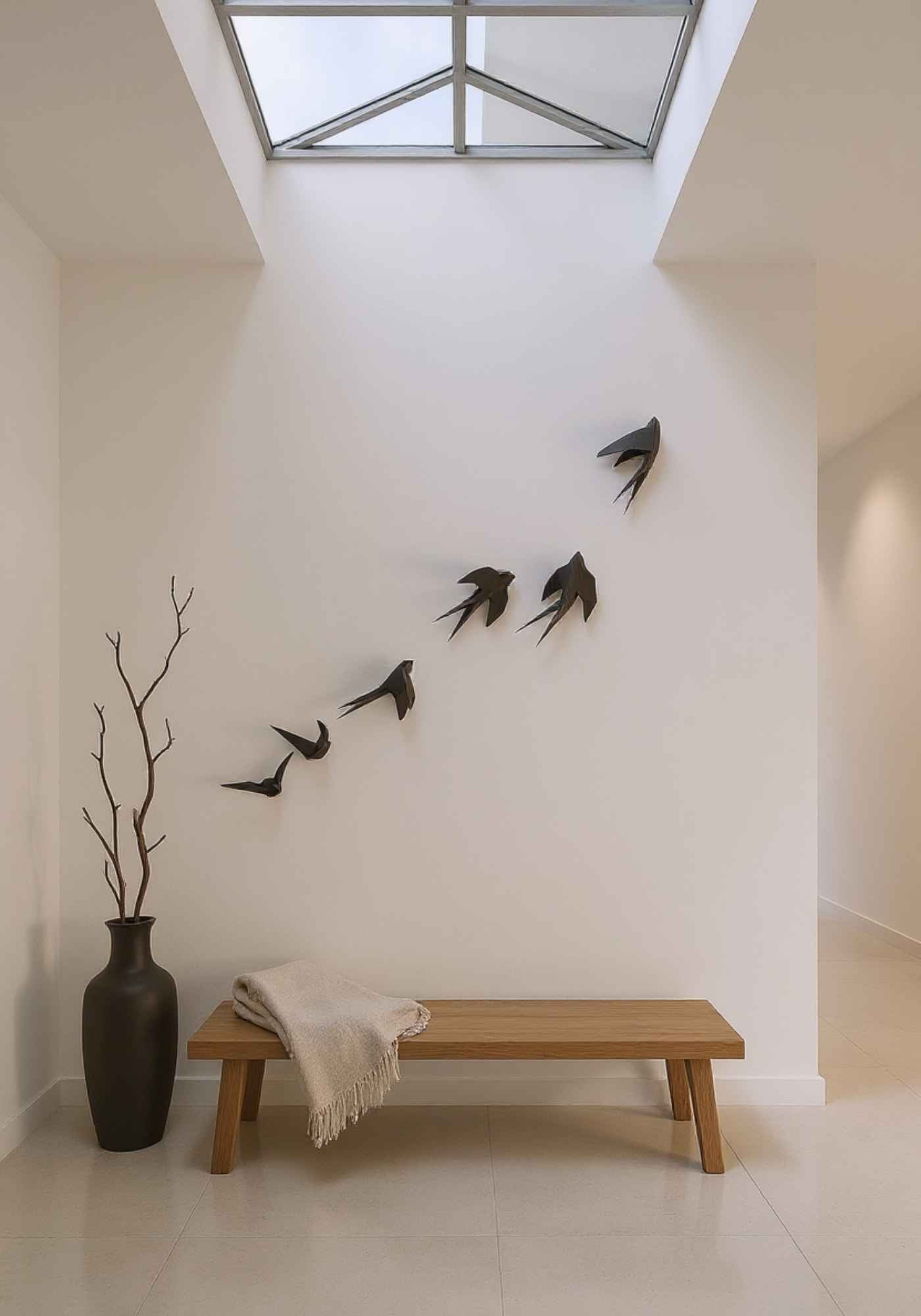Mise en situation du wall art des 6 oiseaux en vol dans une maison. La déco intérieure est accrochée au mur blanc  au-dessus d'un banc.