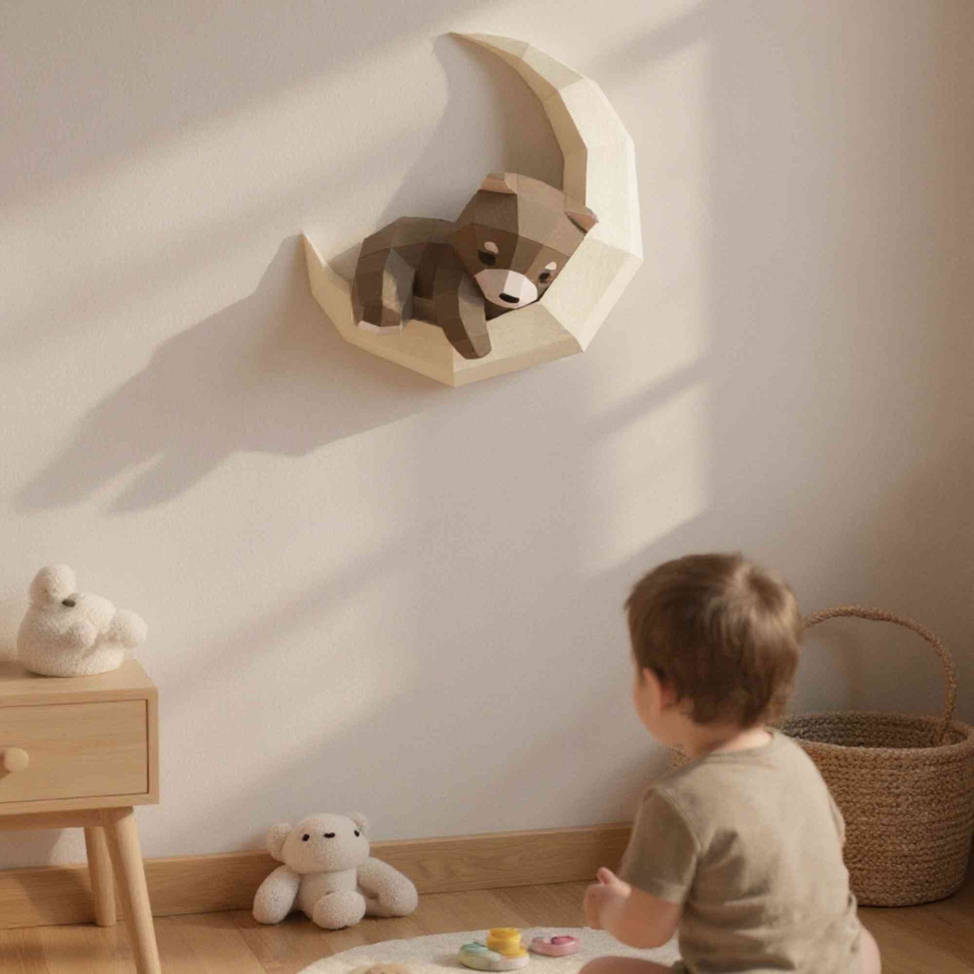 Wall art ourson pour enfant en papier style origami 3D. Créée en papercraft 3D, l'applique murale est un petit ourson en train de dormir sur sa lune. L'applique est accrochée sur le mur d'une chambre d'enfant. On voit un petit garçon de dos en train de regarder le wall art. L'ours est de couleur naturelle.