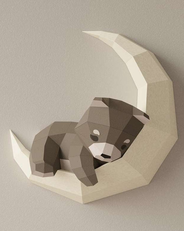 Photo en gros plan du wall art ourson. On voit l'applique murale de l'animal endormi sur la lune accrochée sur un mur. L'ours est en papier papercraft 3D de style japonais origami