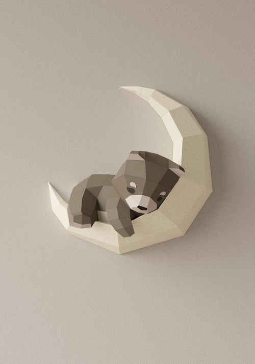 Photo en gros plan du wall art ourson. On voit l'applique murale de l'animal endormi sur la lune accrochée sur un mur. L'ours est en papier papercraft 3D de style japonais origami