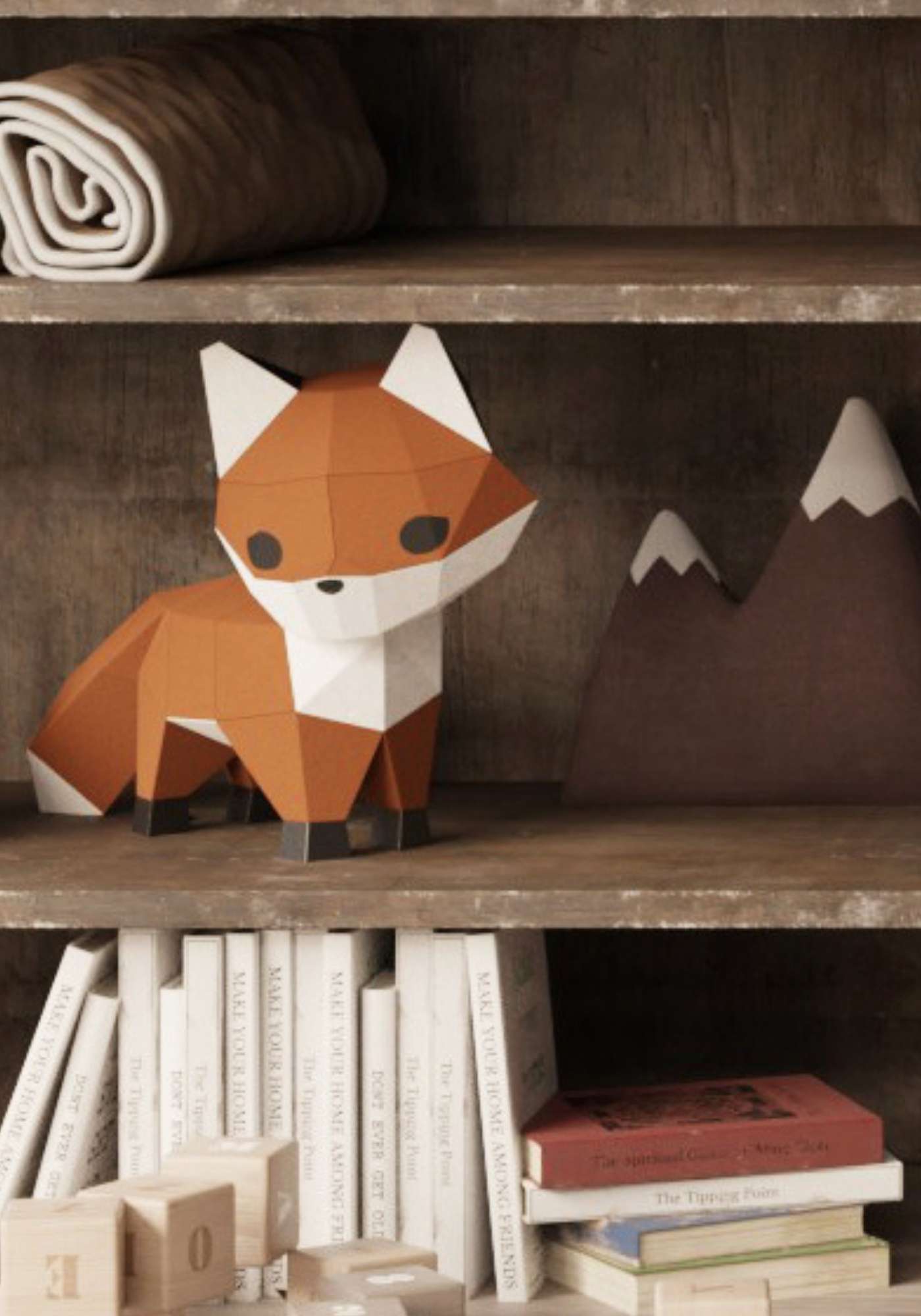 Le renard en papercraft 3D est sur une commode dans une chambre de bébé. On le voit en gros plan entouré de livres d'enfant et autres décorations d'intérieur.