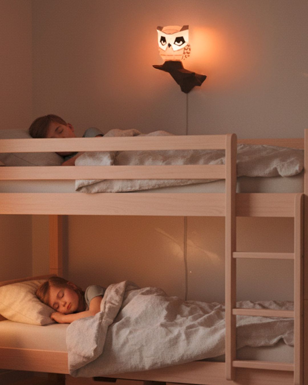 Veilleuse murale hibou en papercraft 3D  de style origami Moki Moki diffusant une lumière douce dans une chambre d’enfant, deux enfants dormant dans un lit superposé.