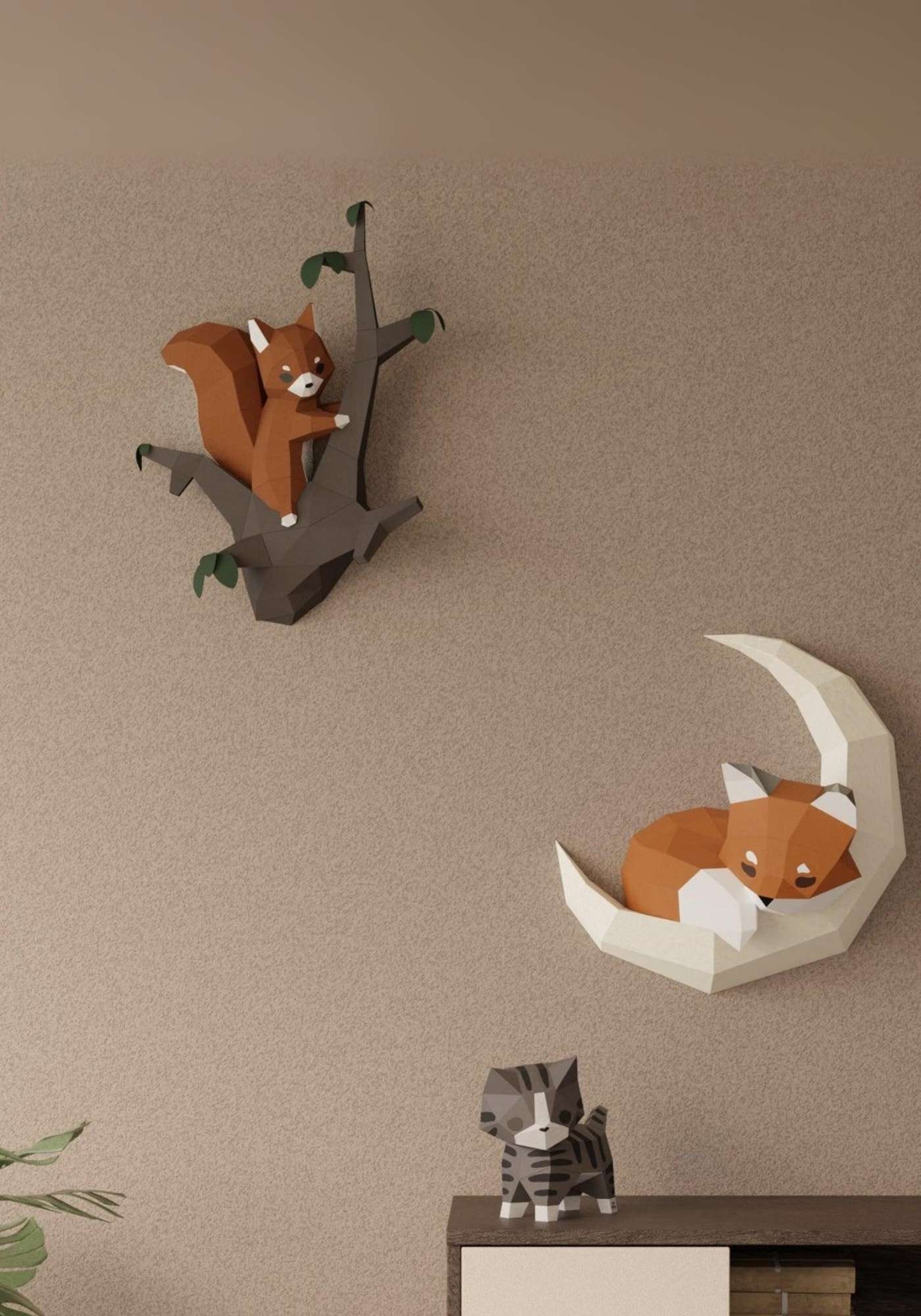 Dans un salon, en décoration intérieure, on voit sur le mur le wall art écureuil et l'applique murale du renard sur la lune. Posé sur une commode, le chat en papercraft 3D. Les créations Moki Moki sont en style origami.